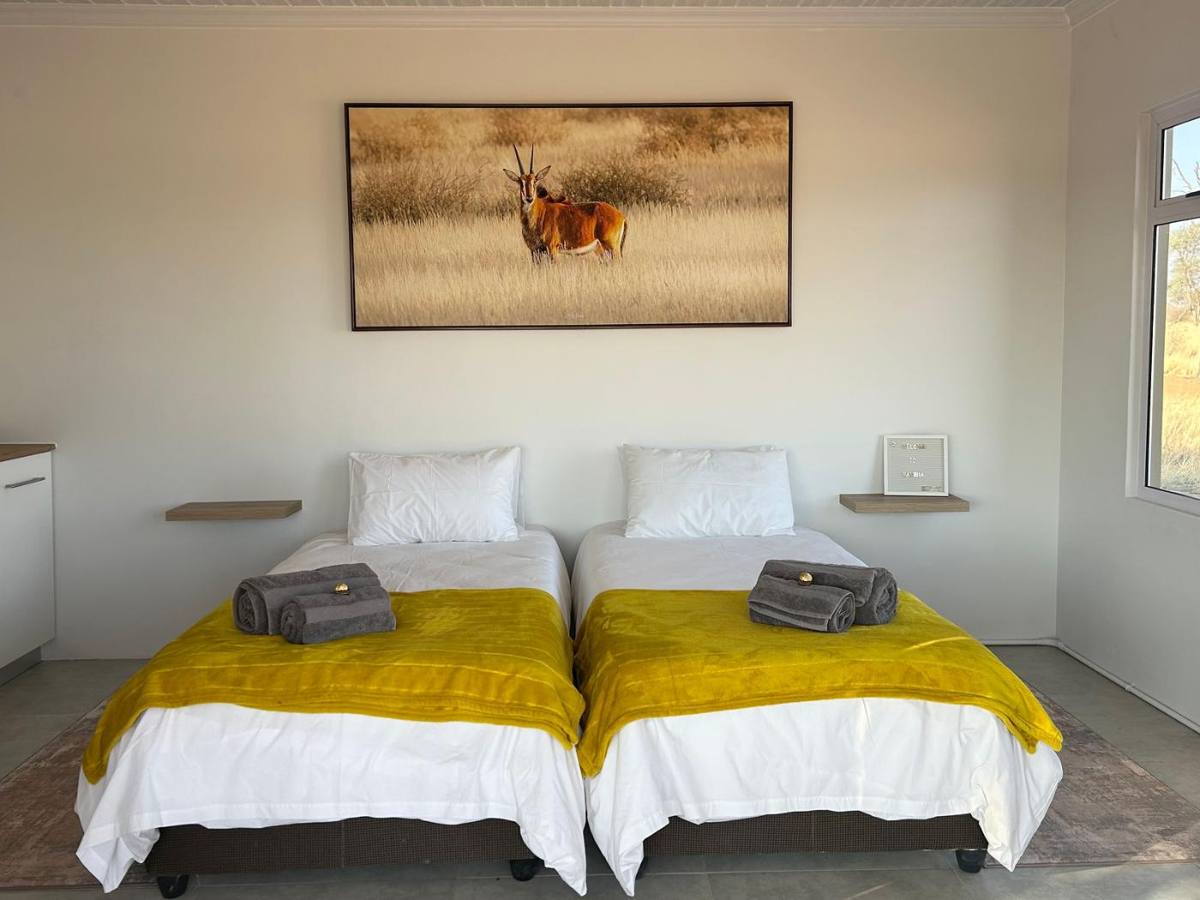 Bedroom with fresh white linen, yellow throws and a springbok painting