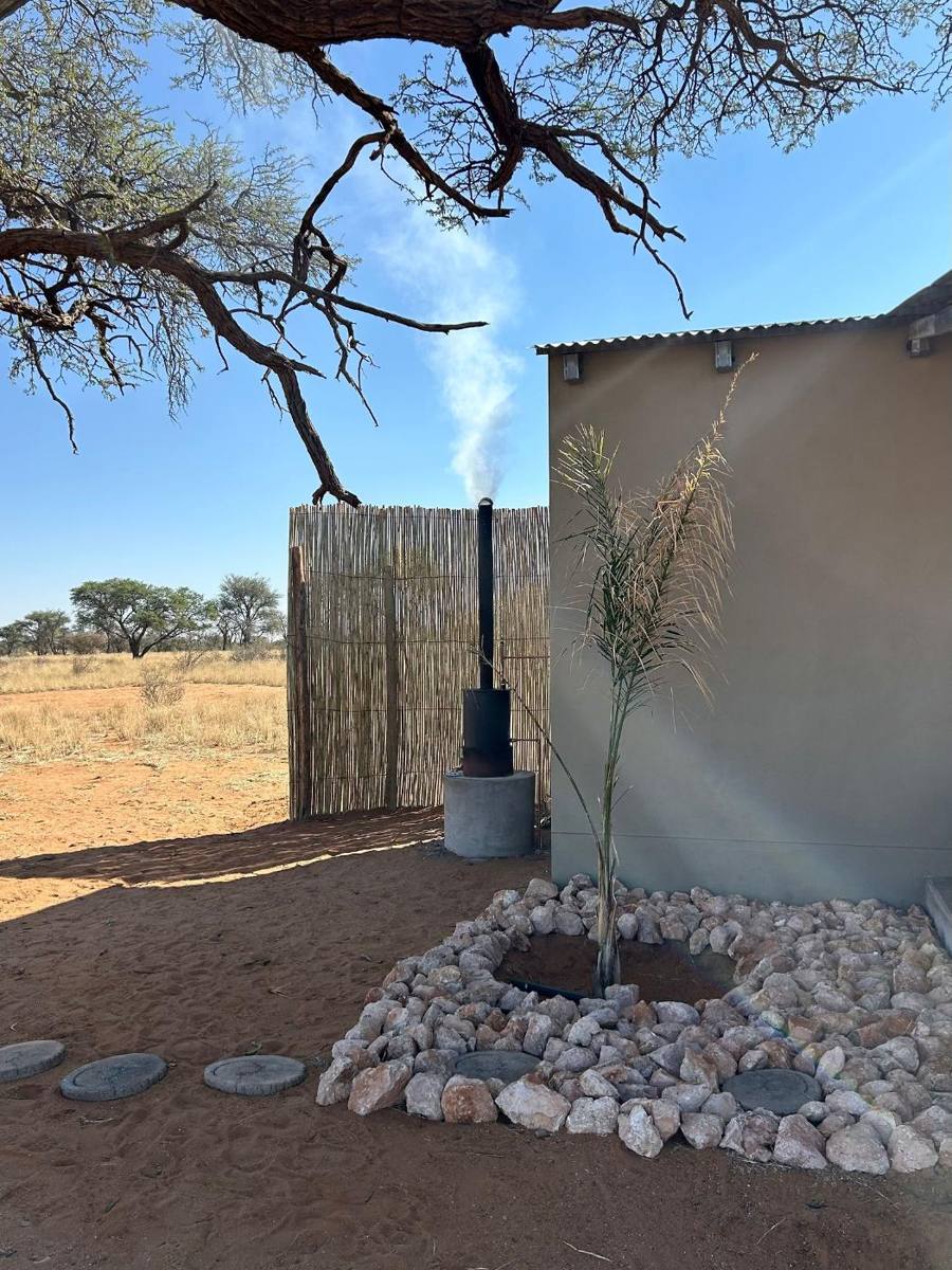 Camel thorn branches over the reed screen and fire-heated water geyser beside a cabin