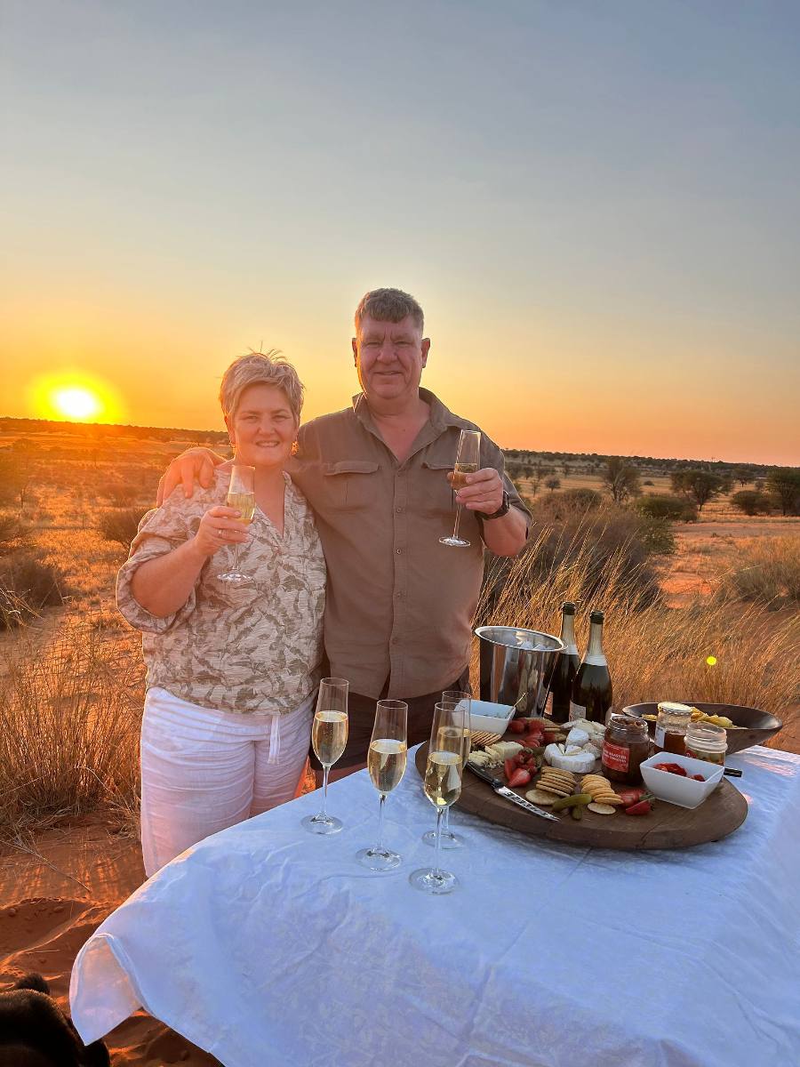 Surita and Hertie Schoeman raising a glass at a sundowner table on the dunes