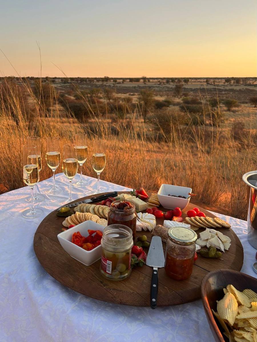 Sundowner table set up on a red dune at golden hour