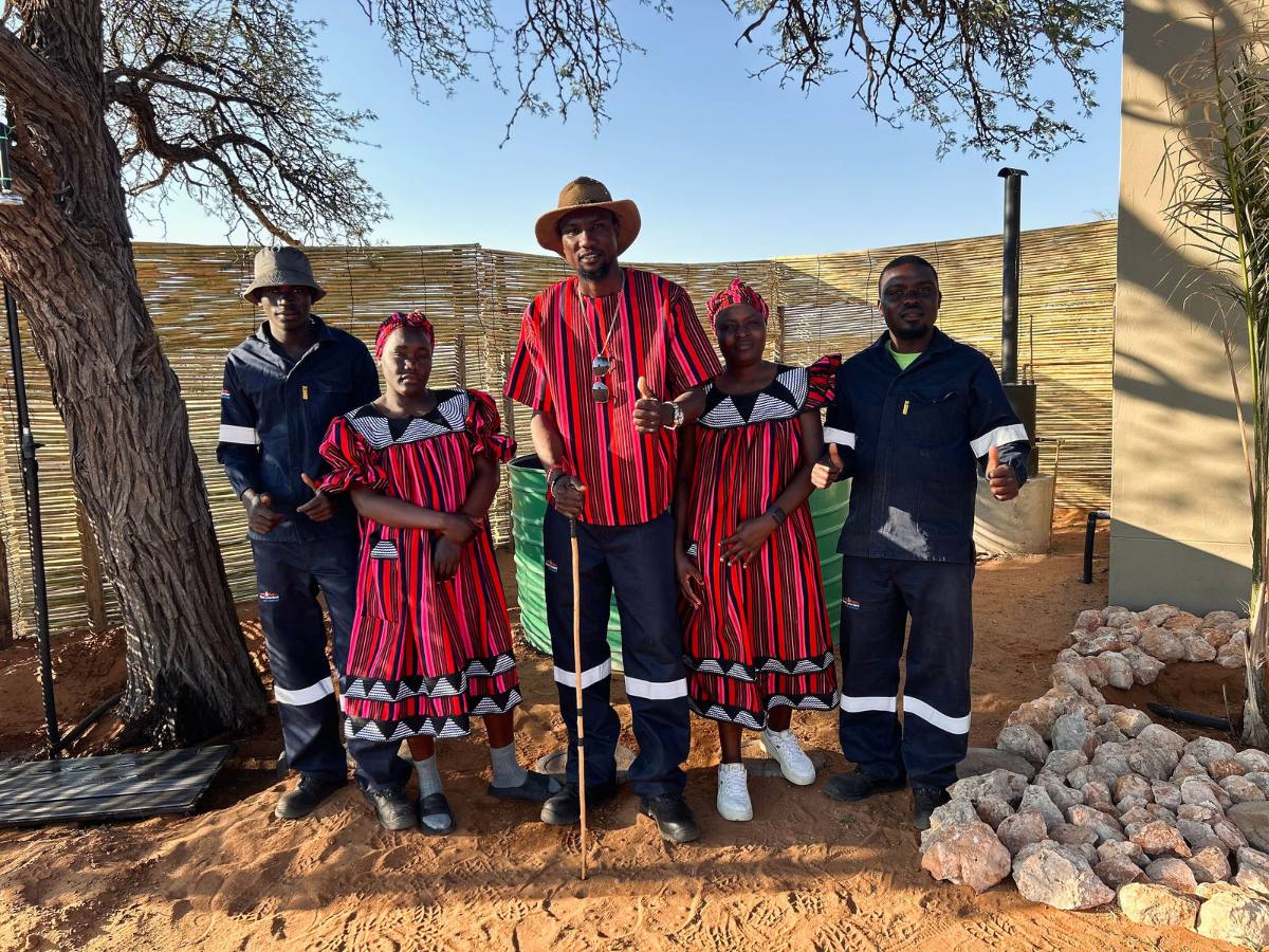 The Munyu farm team standing together in front of the reed fence